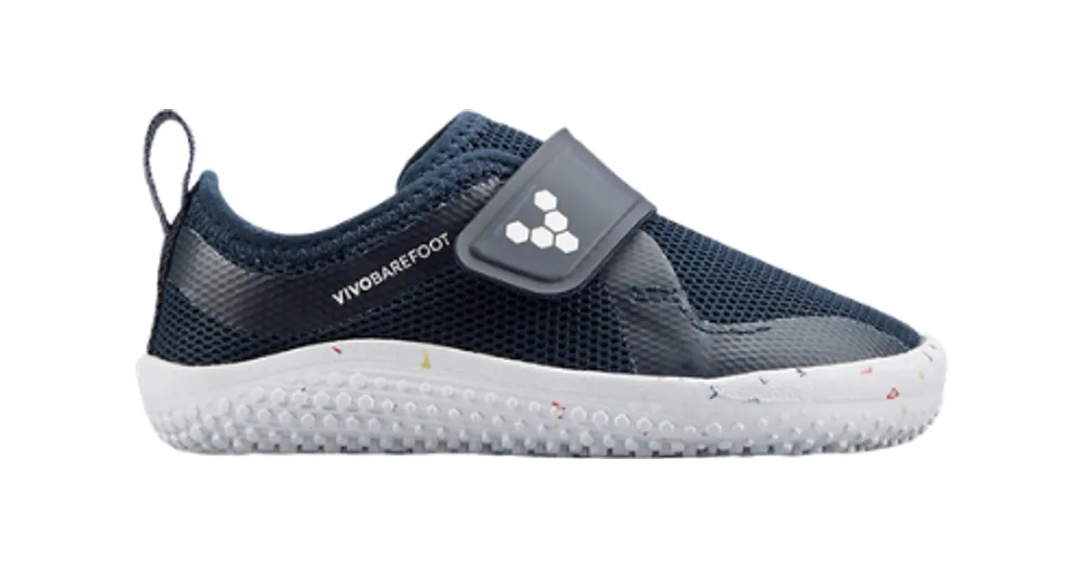 Zapatillas barefoot Vivobarefoot Primus Sport Kids de Vivobarefoot, con puntera ancha y suela plana de 3 mm, en una calle a la luz del día.